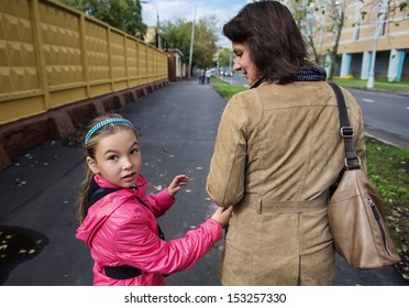 A Little Girl In A Pink Jacket Walking In The Street With Her ??mother. Real People Series.