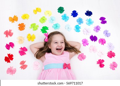 Little Girl In Pink Pastel Dress Choosing Colorful Hair Accessories. Bow And Ribbon For Kids. Hair Style And Accessory For Children. Choice Of Bows. Rainbow Ribbons For Girls. View From Above On White