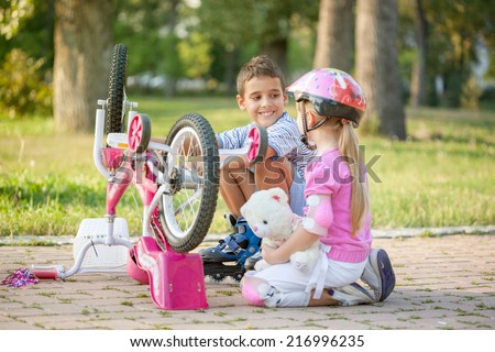 little girl with a pink safety helmet learns how to fix  bike