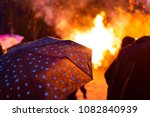 A little girl with a pink umbrella watching a bonfire in Orebro, Sweden