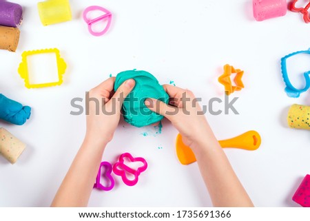 Little girl play with modeling clay on white background. Top view. Home Education game with clay. Early development concept