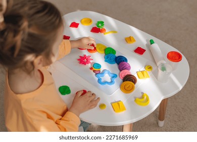 A little girl play with plasticine and creates colorful numbers.  Learning to count through play. Early education. Fine motor skills, creativity and  hobby.