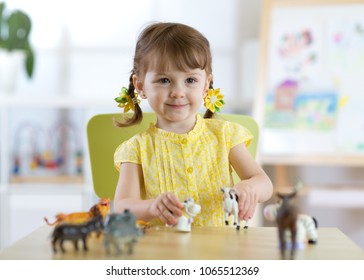 Little Girl Playing With Animal Toys In Playroom