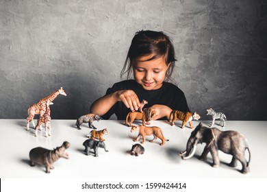 Little Girl Playing With Animal Toys In Playroom