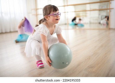 Little girl playing with ball at ballet class in dance studio. Concept of integration and education of disabled children. - Powered by Shutterstock