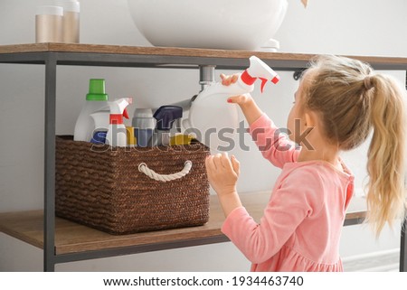 Little girl playing with cleaning supplies at home