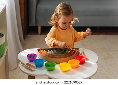 A little girl playing colored rice and make rainbow. Child filled the rainbow with bright rice. Montessori material. Sensory play and learning colors activity for kids. 