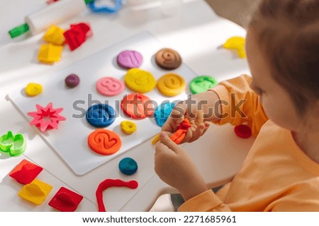 A little girl playing with colorful pieces of plasticine. Art Activity for Kids. Fine motor skills, creativity and  hobby. Sensory play for toddlers.
