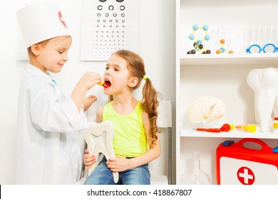 Little girl playing a dentist with her friend