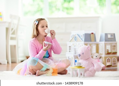 Little Girl Playing With Doll House In White Sunny Bedroom. Kid With Toys. Role Game For Young Children. Child With Teddy Bear Toy. Kids Play Tea Party With Stuffed Animals And Dolls. Nursery Interior