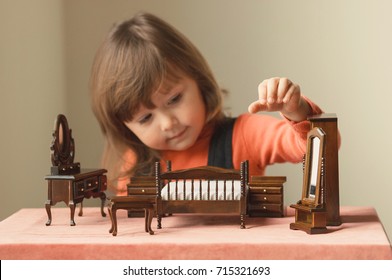 Little Girl Playing With Doll House Furniture