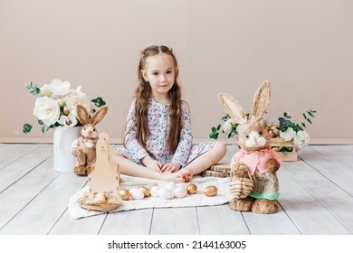 Little Girl Playing With Easter Toy Bunnies And A Basket Of Easter Eggs. Child Celebrating Easter. Easter Egg Hunt. Home Decoration, Bunnies And Flowers