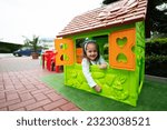 Little girl playing in green plastic kid house at children