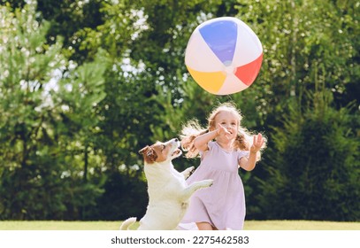 Little girl playing with her pet dog and beach ball at backyard lawn on summer day - Powered by Shutterstock