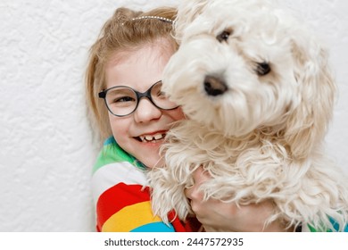 Little girl playing with her pet dog Maltese at home. Happy child and cute puppy. Love, friendship, family animal. - Powered by Shutterstock