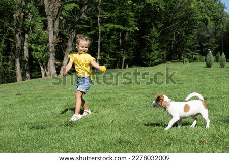 Little girl playing with her pet dog Jack Russell Terrier in park