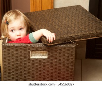 Little girl playing hide and seek in brown box