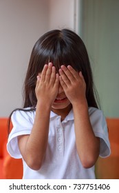 little girl is playing hide-and-seek hiding face.