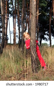 Little girl playing hide-and-seek in the pine forest