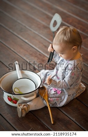 A little girl is playing with large pots and ladles. Foto stock © 