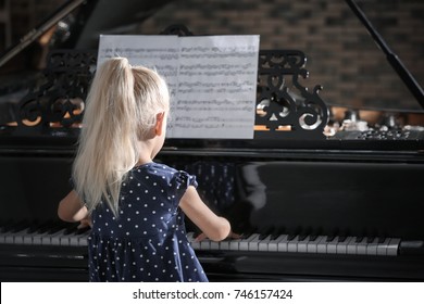 Little Girl Playing Piano At Concert Indoors