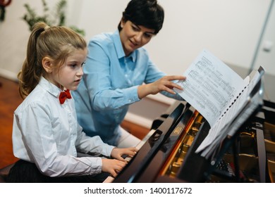 little girl playing piano with her teacher
