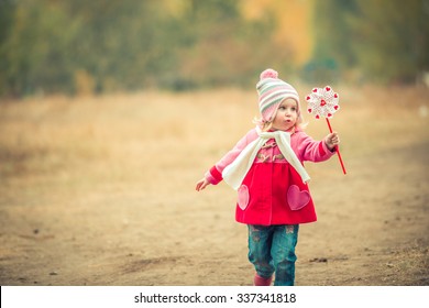 little girl playing pinwheel toy walking on autumn landscape - Powered by Shutterstock