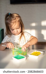 Little girl playing with sensory water beads, hydrogel balls. Sensory development and experiences, Montessori, themed activities with children, fine motor skills development