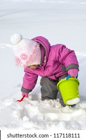 Little girl playing with snow, spade and pail - Shutterstock ID 117118111