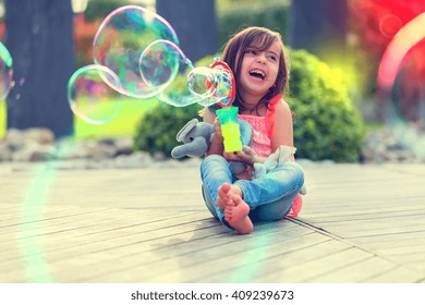 Little girl playing with soap bubbles machine