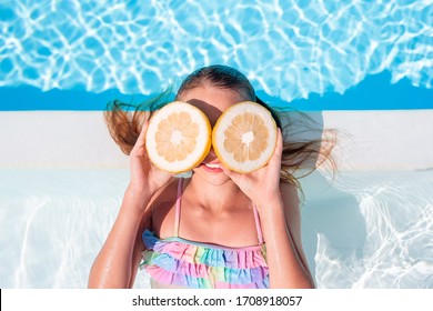 Little girl playing and splashing in an exotic resort at swimming pool