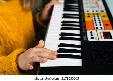 a little girl playing the synthesizer, the concept of teaching children music, hands close-up.