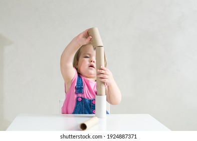 Little girl playing with toilet paper rolls and cardboard tube. Games and toys made paper tube for babies and toddler, activities Montessori in our home, child development and occupational therapy