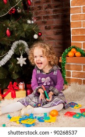 Little Girl Playing With Toys Near Christmas Tree