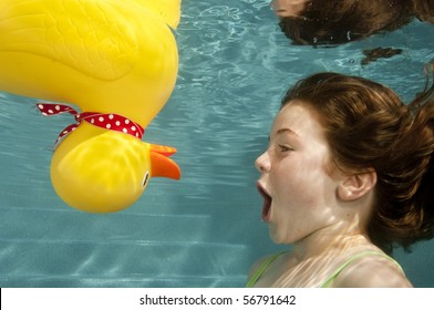 Little Girl Playing Underwater With Large Yellow Rubber Duck