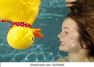 Little Girl Playing Underwater With Large Yellow Rubber Duck