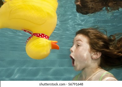 Little Girl Playing Underwater With Large Yellow Rubber Duck