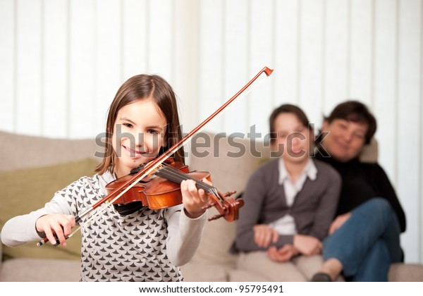 little girl\
playing violin with her family at\
home