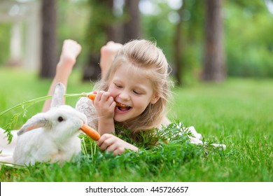Little girl playing with white rabbit in summer day outdoor