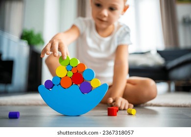 Little girl playing with wooden balancing toy on the floor in home living room. Focus on balancer. High quality photo - Powered by Shutterstock