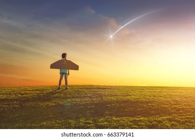 Little girl plays astronaut. Child on the background of sunset sky. Kid is looking at falling star and dreaming of becoming a spaceman.