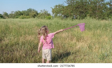 Little girl plays with butterfly net of tall grass in city park. Cute little girl is playing with aerial insect net in meadow on sun day. - Powered by Shutterstock