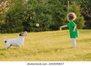 Little girl plays with pet dog on backyard lawn throwing toy ball to catch - Powered by Shutterstock