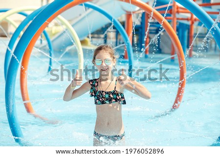 Little girl plays in the pool, in the water park