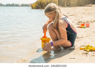 Little girl plays with sand on the beach. Summer activities for kids concept. - Powered by Shutterstock