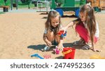 A little girl plays in the sandbox. Friendly sisters play together in the fresh air. Family summer holiday concept