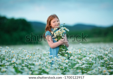 Little girl posing on a field of flowers camomile. Summertime vacation fun in rustic vilage