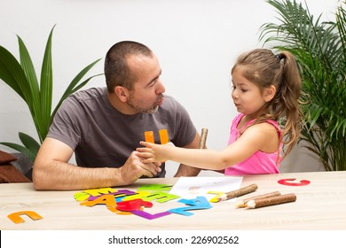 A little girl practicing the alphabet with her father