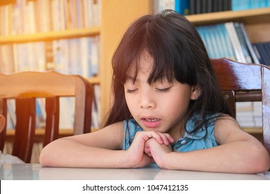 Little Girl Praying In The Classroom.Little Asian Girl Hand Praying,Hands Folded In Prayer Concept For Faith,spirituality And Religion.Black