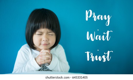 Little girl praying in the morning.Little asian girl hand praying,Hands folded in prayer concept for faith,spirituality and religion.Pray Wait Trust Text.
